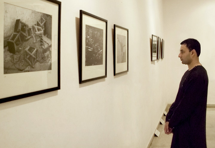 Mayank looking at framed photographs from the 'Out of the Ordinary' series displayed in an art gallery