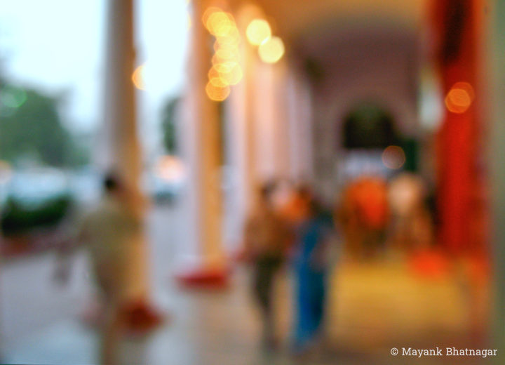 People in an open pillared corridor of Connaught Place, with an archway behind