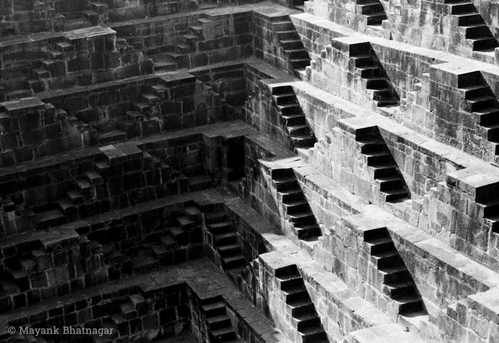 Geometric stairs connecting different levels of a step well, half in shade and about half in light