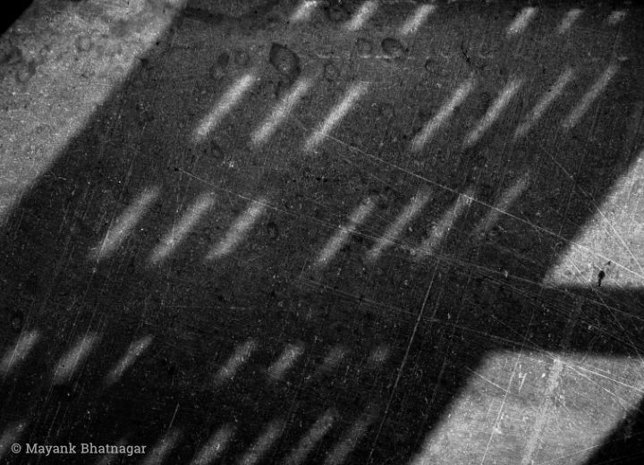 Diagonal streaks of light and shade from a window falling on scratched floor