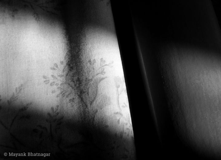 Soft morning sunlight from a window falling on a bed and highlighting the floral design of the bedcover