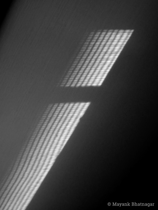 Close-up of light coming in from a meshed window falling on a room curtain