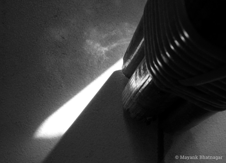 Close-up of a streak of sunlight falling on the floor, right beside the leg of a cane chair