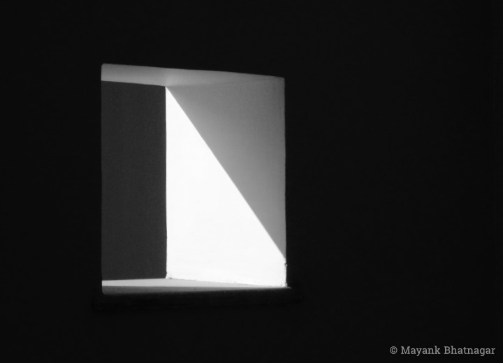 Minimalistic black and white photograph of light falling diagonally inside a square ventilator