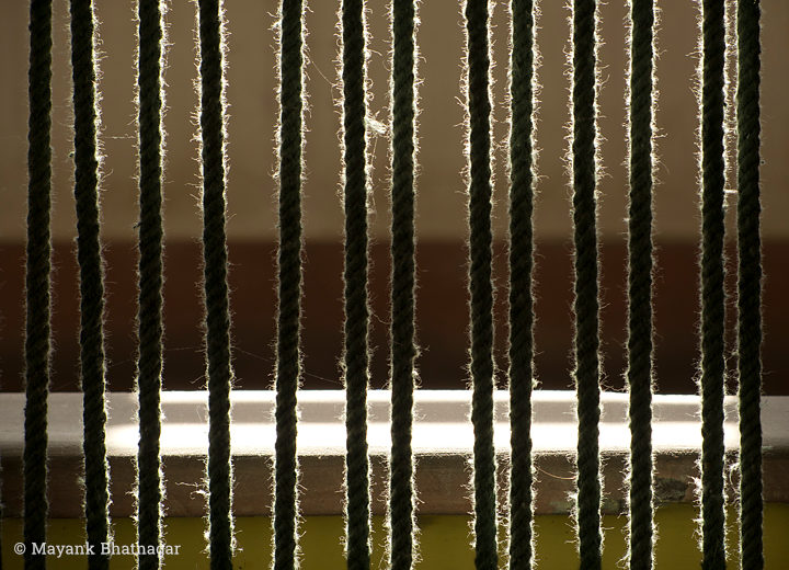 Threads of parallel vertical ropes illuminated by light falling from behind