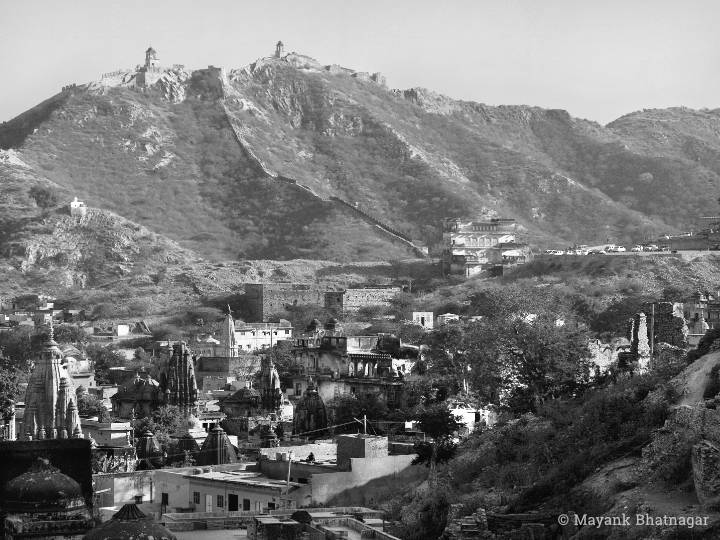 Landscape photo of Amer with old temples in the foreground and ramparts on hills in the background