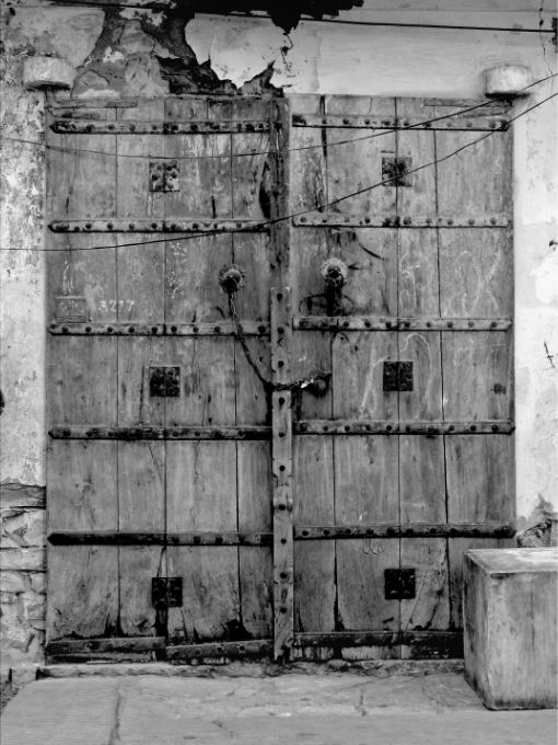 A heavily textured, closed wooden door locked by a chain