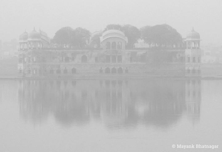 Jal Mahal and its reflection in the still lake below, faintly visible through haze