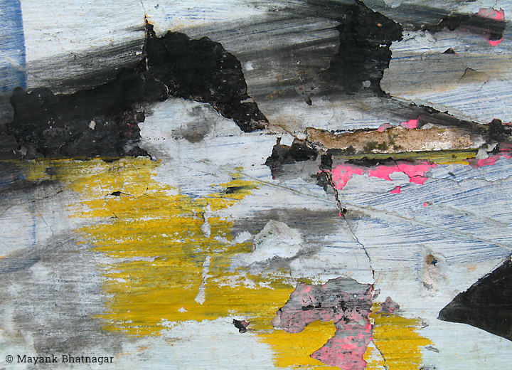 Peeling plaster and remnants of black, yellow and pink paint over fine, old paintbrush marks