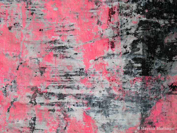 Remnants of scratched pink and black paint over a light grey textured background