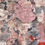 Many layers of torn paper and paint peeling off an old wall, in dominant pink hues