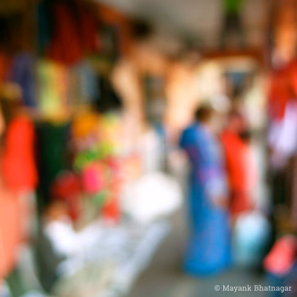 Impressionistic, artistic fine art photograph of saree-clad women shopping for colourful clothes displayed at a Jaipur market