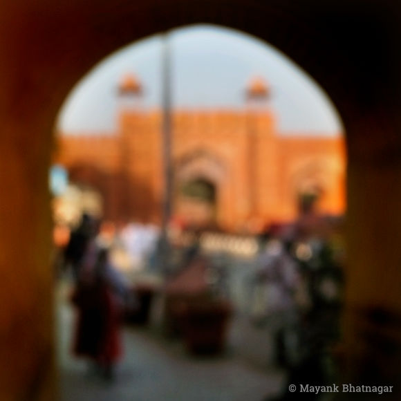 A large, pink or 'geru' coloured arched gateway with people in the foreground
