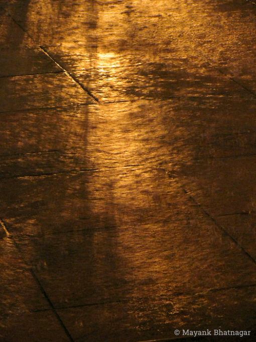 Reflection of warm yellow light over moving rainwater on the floor
