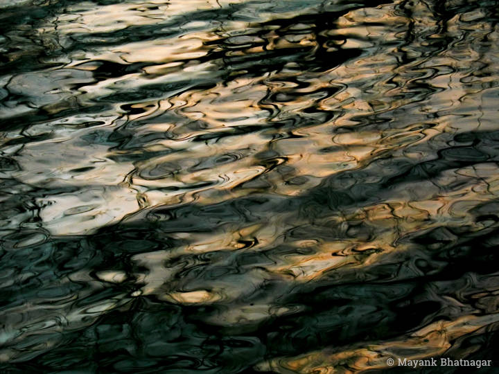 Photo of ripples in black, white and light orange colours, with play of light and shade
