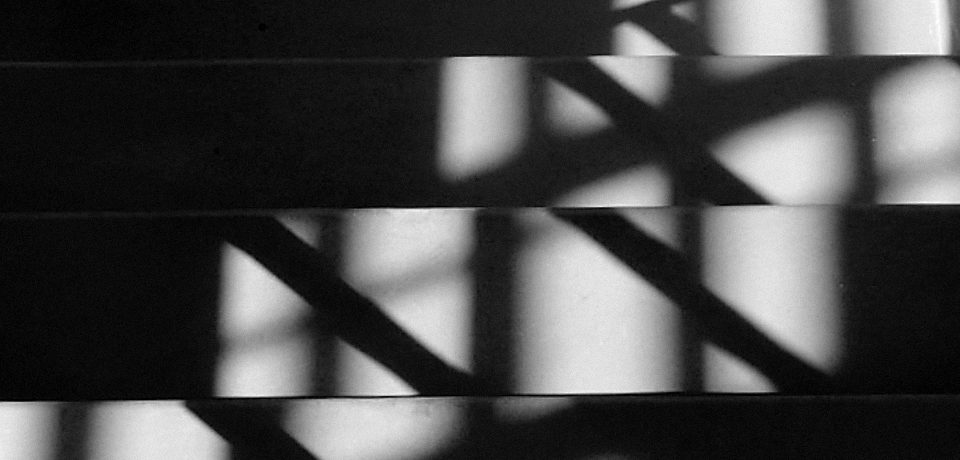 Black and White photograph of light from a window falling on stairs and creating a zig-zag pattern