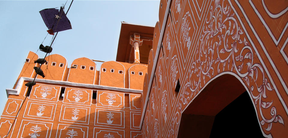 A large city gate in perspective, with leafy decorative patterns painted on it